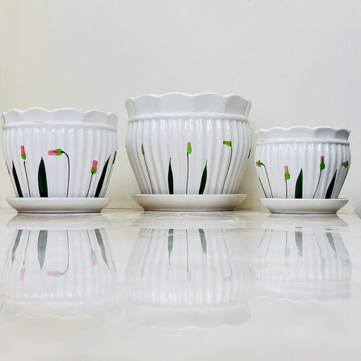 White ceramic pots with pink floral accents and scalloped edges