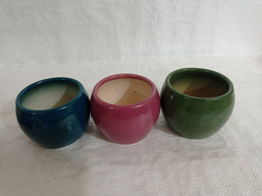 Trio of elegant round ceramic plant pots in dark blue, turtle green, and wine color